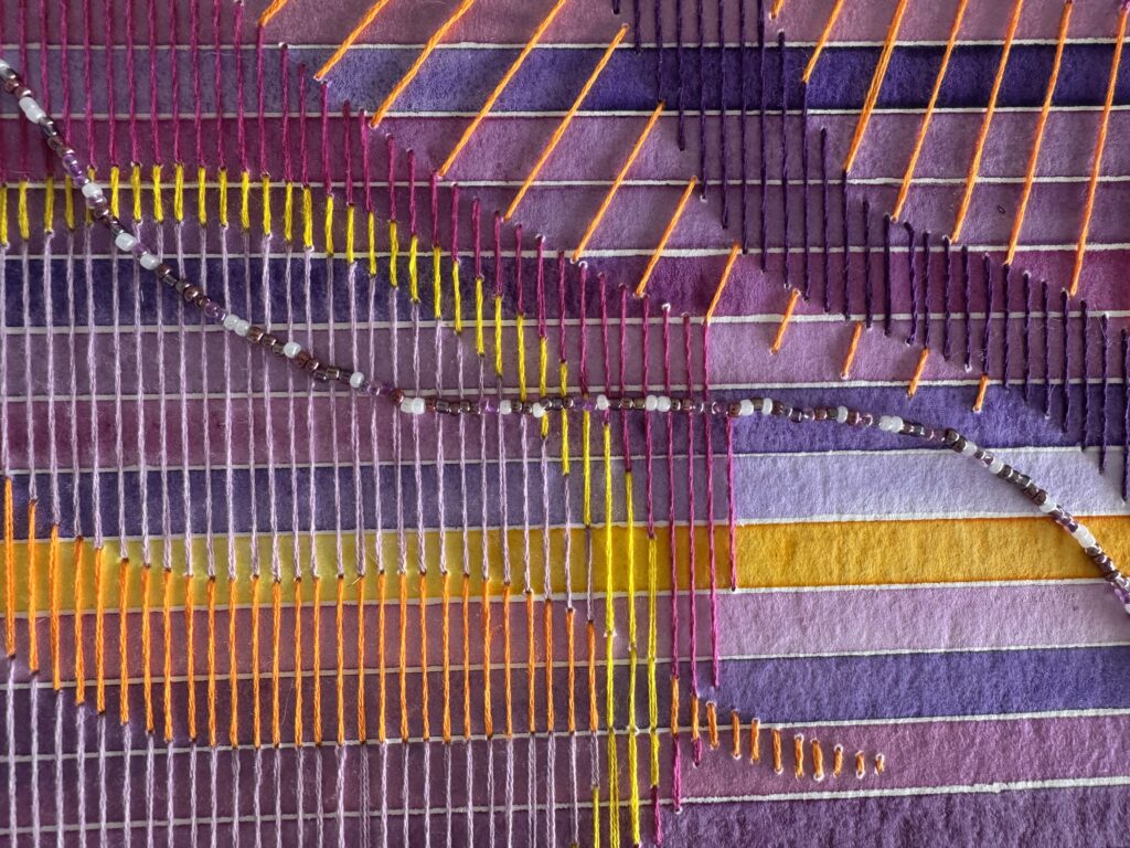 gros plan sur les détails d'une aquarelle brodée de fils et de perles