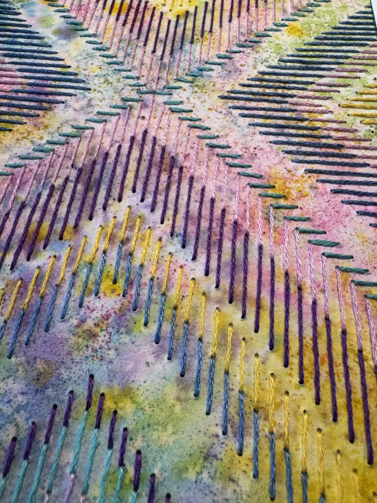 gros plan d'une aquarelle brodée aux motifs géométriques